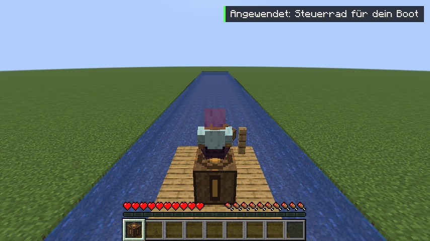 Selbst gebautes Floß mit Steuerrad fährt einen Kanal entlang